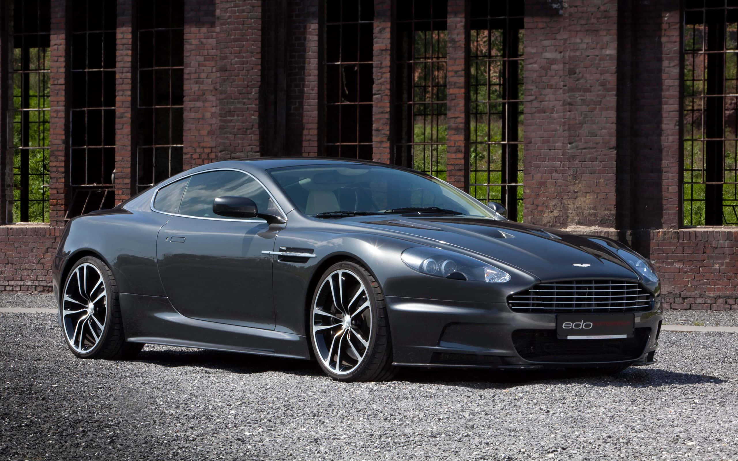Aston Martin DB9 สีเงินสวยงามบนสนามแข่ง วอลเปเปอร์