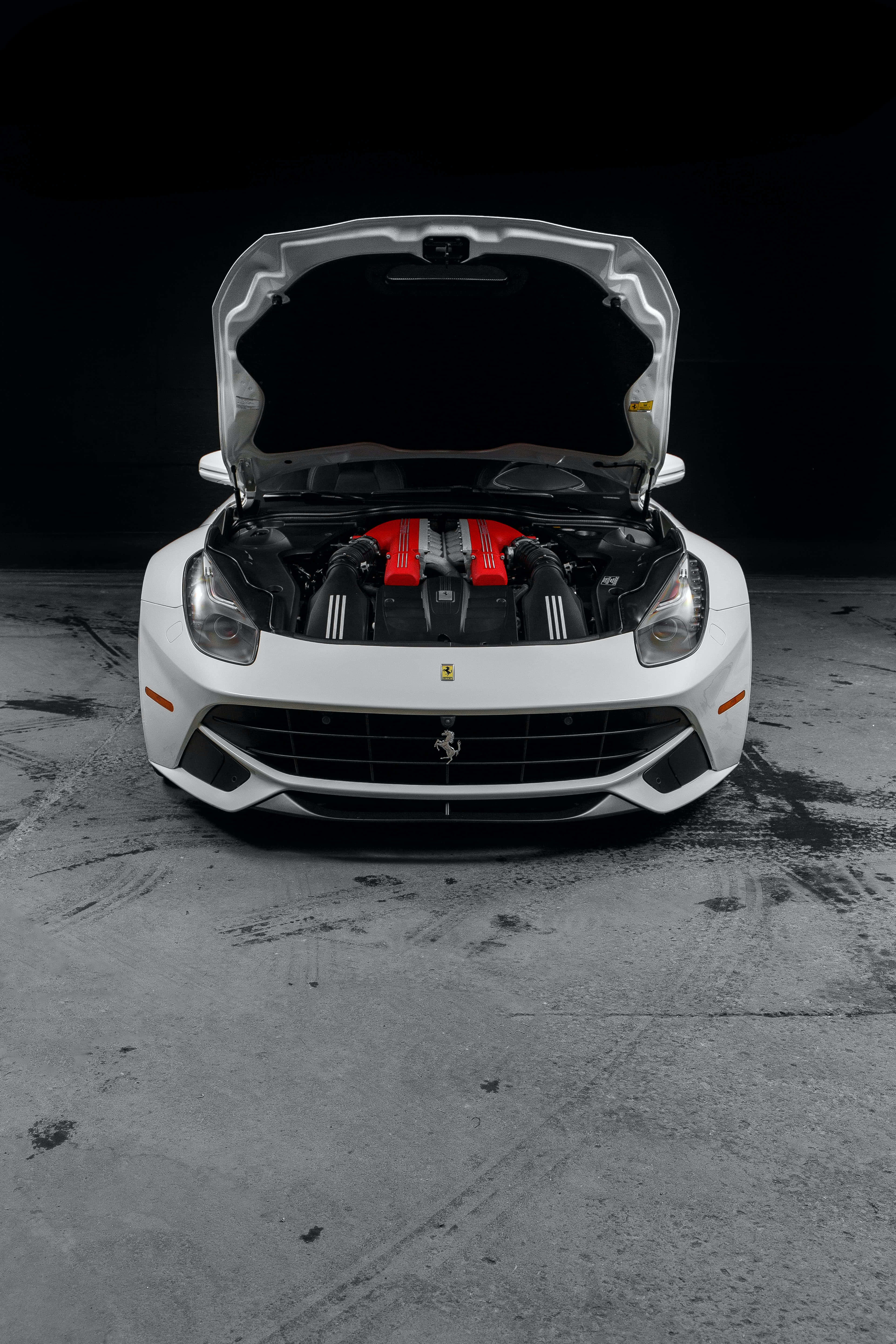 รถเฟerrari สีแดงความเร็วสูงตระหง่านท่ามกลางท้องฟ้าพลบค่ำ วอลเปเปอร์