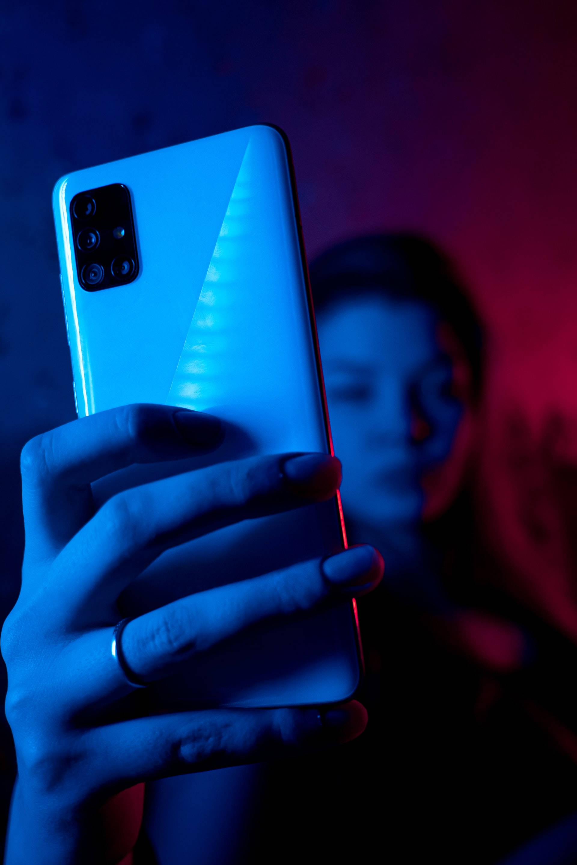 ผู้หญิงกับโทรศัพท์ในแสงนีออนสีน้ำเงิน iPhone วอลเปเปอร์