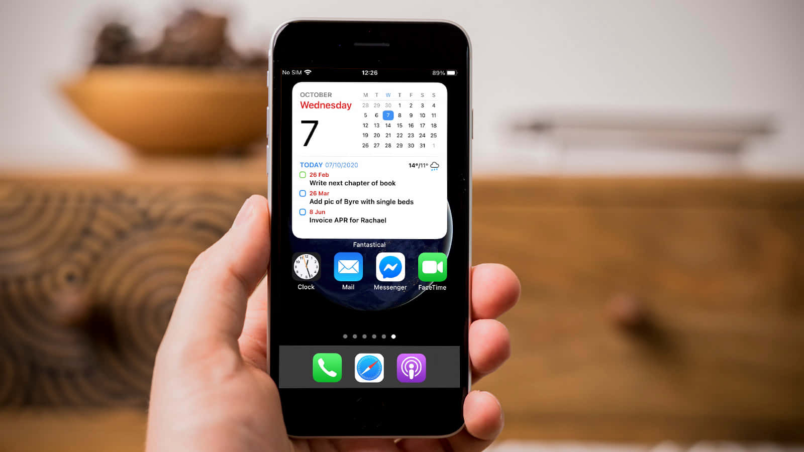 คนถือ iPhone ที่มีปฏิทินอยู่บนหน้าจอ วอลเปเปอร์