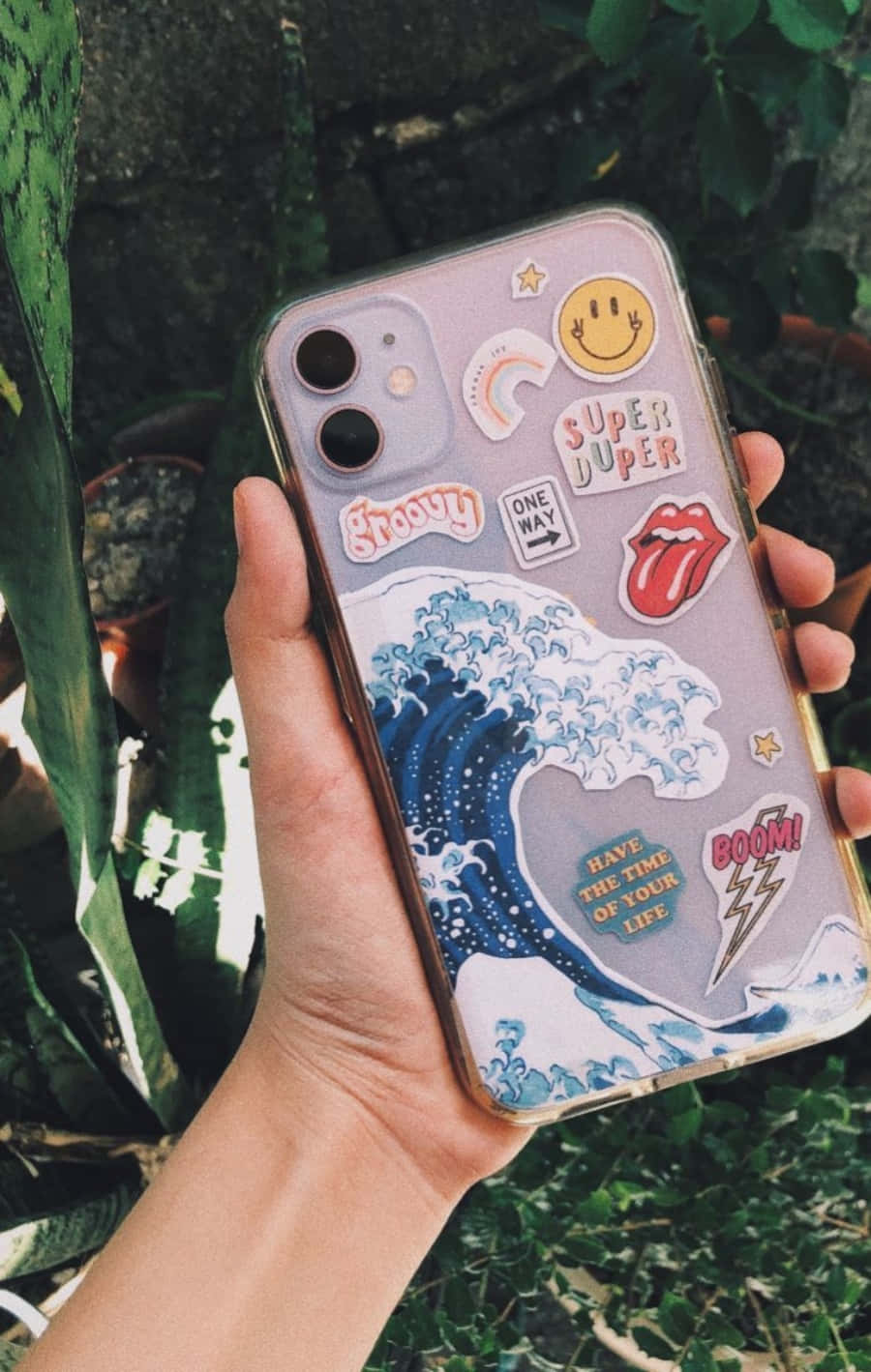 คนถือเคสโทรศัพท์ที่มีสติกเกอร์ติดอยู่ วอลเปเปอร์