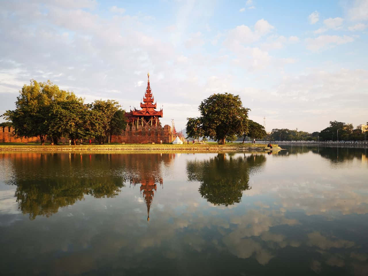 คูน้ำล้อมรอบด้วยต้นไม้งามตรงกลางที่พระราชวังมัณฑะเลย์ วอลเปเปอร์