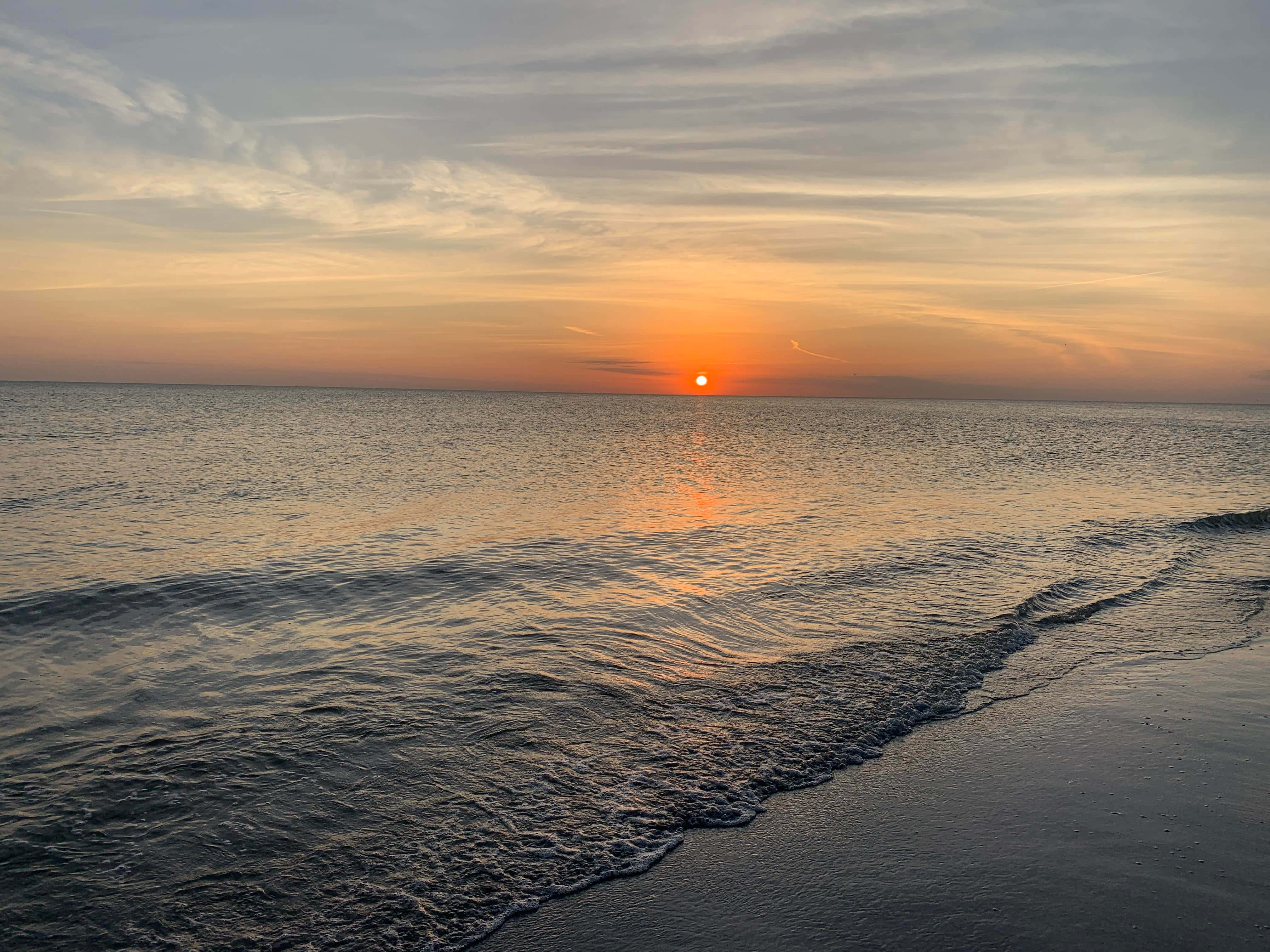 ซึมซับสีสันสดใสของพระอาทิตย์ตกที่ชายหาด วอลเปเปอร์