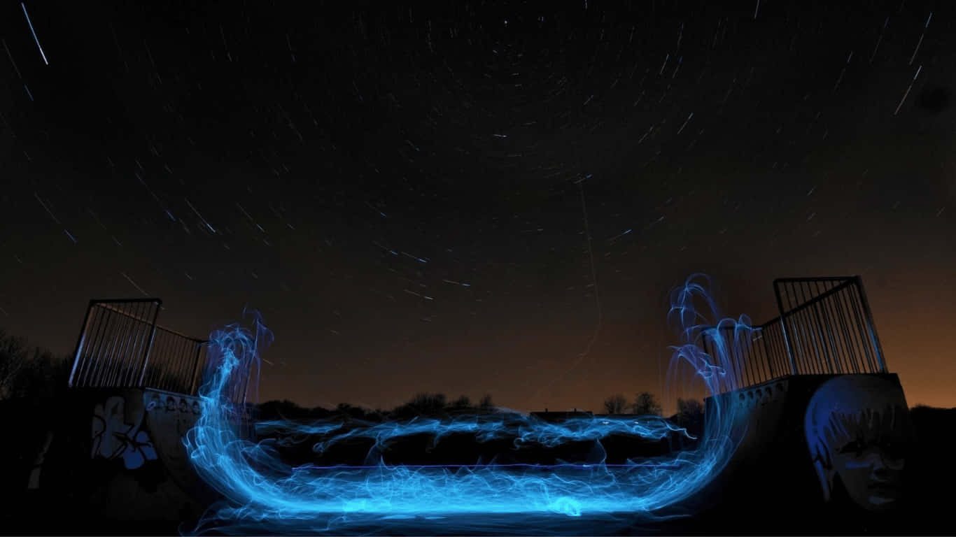 นักสเก็ตบอร์ดกำลังเล่นสเก็ตในความมืดพร้อมแสงสีฟ้า วอลเปเปอร์