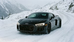 รถ Audi R8 สีดำขับผ่านถนนบนเทือกเขาที่มีหิมะตก