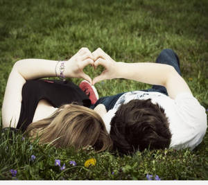 คู่รักน่ารักทำรูปหัวใจบนพื้นหญ้า