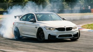 BMW M4 สีขาวดริฟต์เข้าโค้งบนสนามแข่งพร้อมควันยางและภาพเบลอจากการเคลื่อนไหว — BMW วอลเปเปอร์